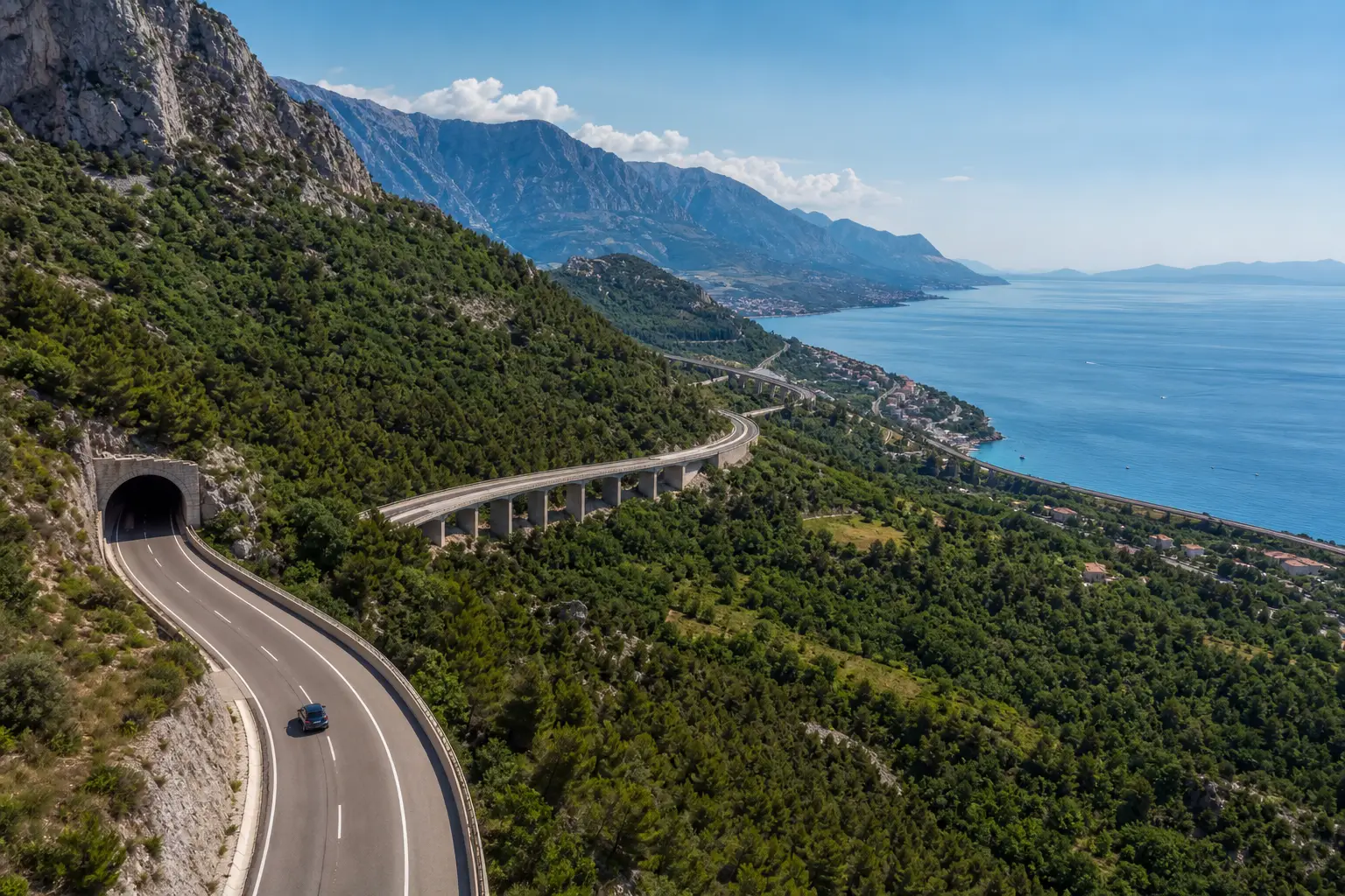 Kurvige Küstenstraße mit Tunnel und Viadukt hoch über der Adria auf dem Weg nach Kroatien.