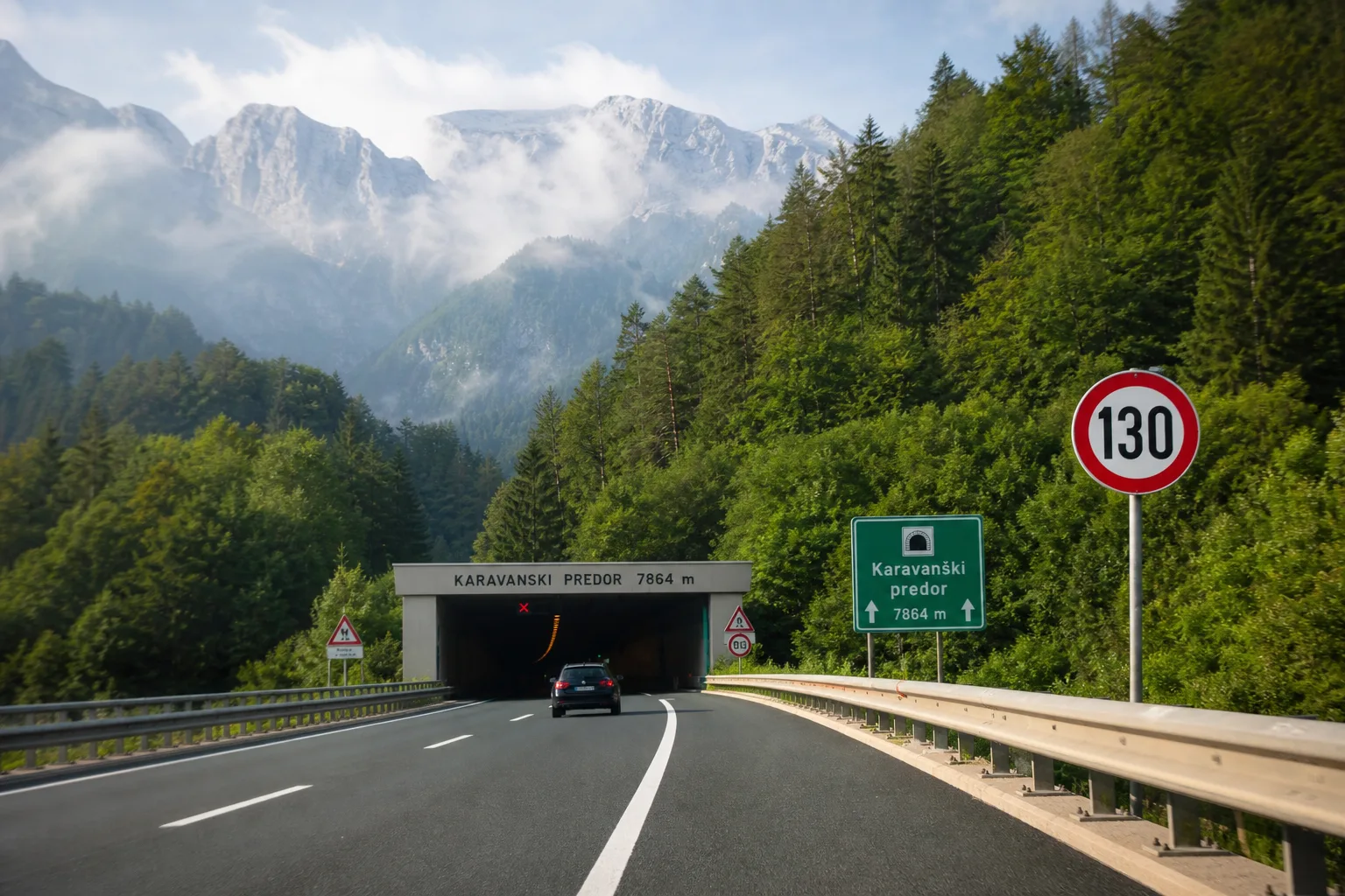 Slowenische Autobahn vor den grünen Julischen Alpen Richtung Karawankentunnel mit einem 130er-Schild – das Tempolimit in Slowenien.