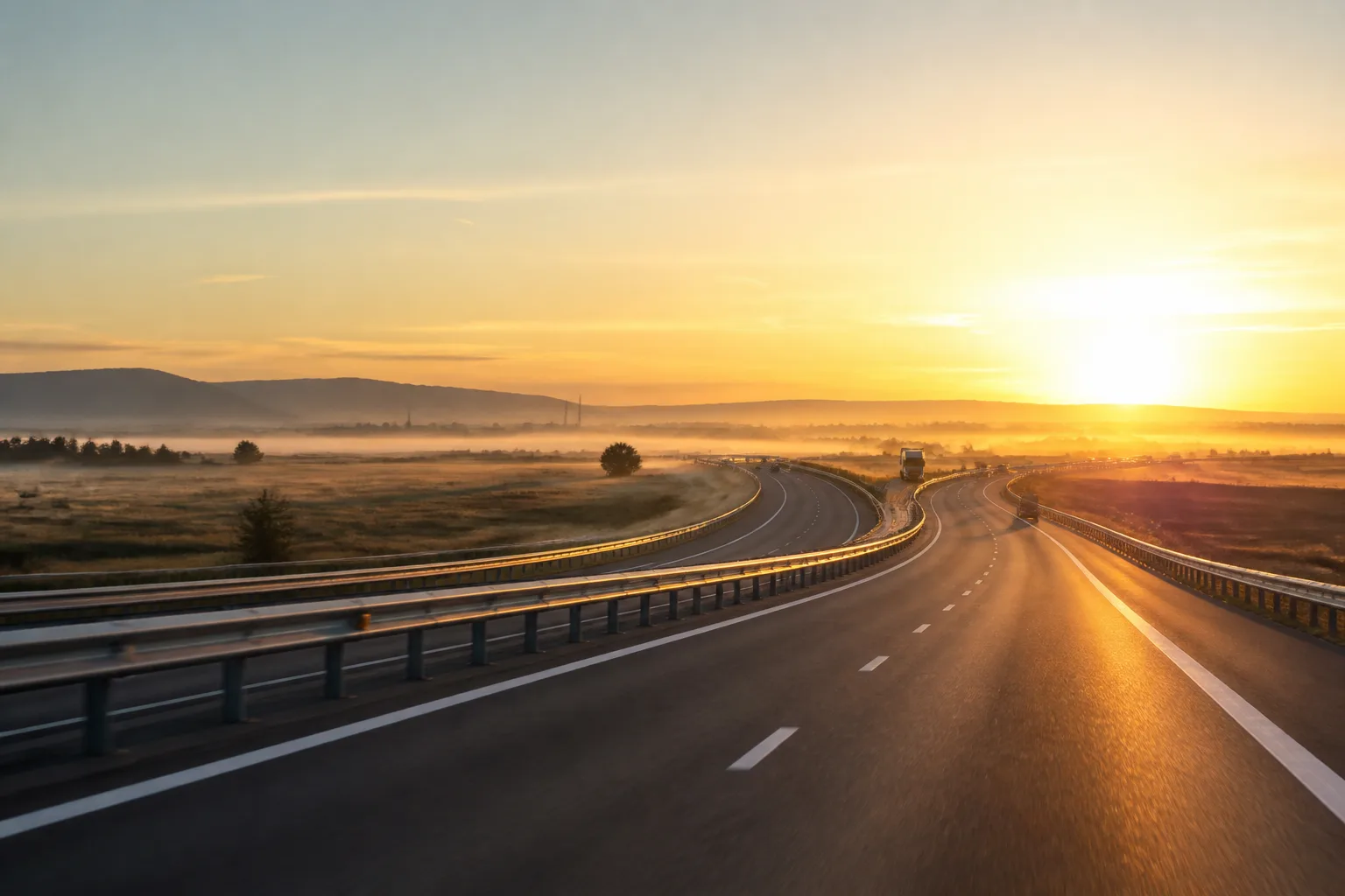 Autostradă din România în lumina răsăritului, cu ceață subțire deasupra câmpurilor.