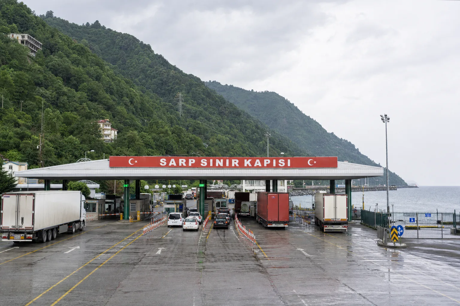 Karadeniz kıyısında, yemyeşil dağların eteğindeki modern Sarp Sınır Kapısı terminali ve gümrük geçiş şeritleri.