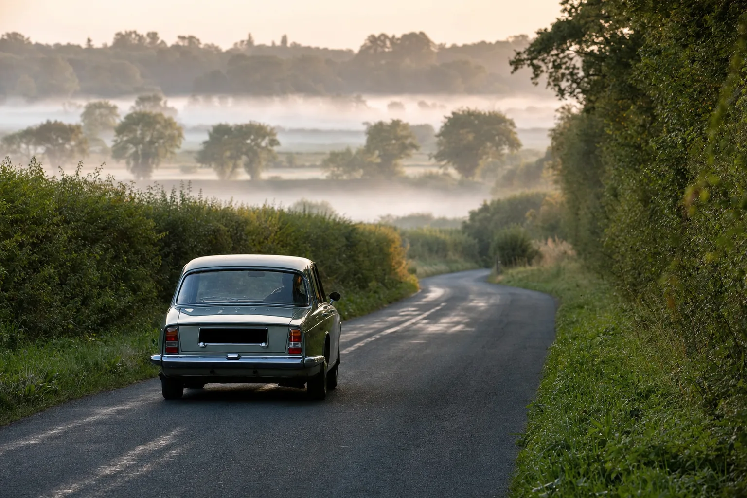 A classic British car keeps to the left on a narrow hedgerow-lined country lane, the driving habit the UK wrote into law in 1835.